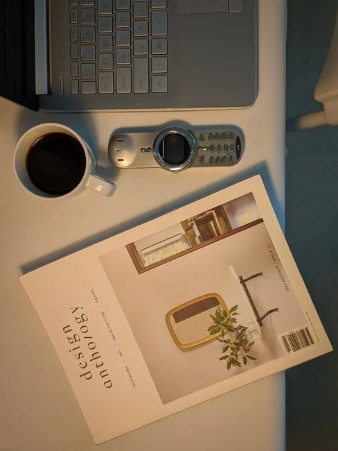 Gros plan sur un carnet contenant des esquisses de wireframe et un smartphone posés sur un bureau en bois.